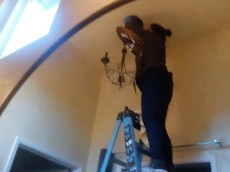 Electrician installing a chandelier in a Dakota Ridge residence